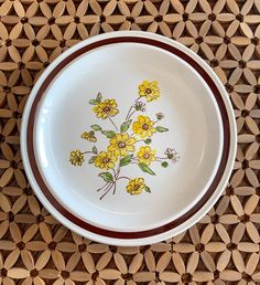 a white bowl with yellow flowers painted on the side and brown trim around the rim