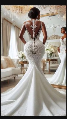 a woman in a white wedding dress looking at herself in the mirror with her back to the camera