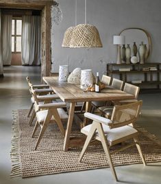 a dining room table with chairs and vases on the floor in front of it