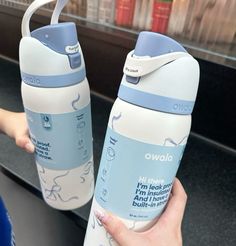 two water bottles being held up by someone's hand