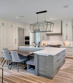 a kitchen with white cabinets and an island in front of the countertop, surrounded by chairs