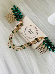 a close up of a brooch and hair comb on a white cloth with a card