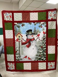 a quilted snowman is hanging on the wall in front of a christmas tree