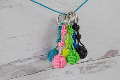 several different colored bracelets hanging from a string on a white wooden surface with a blue cord