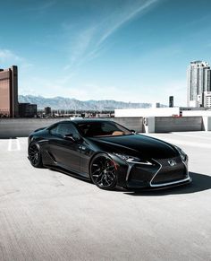 a black sports car parked in front of some tall buildings with mountains in the background