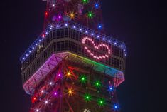 the tokyo tower is lit up with colorful lights