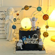 a birthday cake with an image of the planets on it and two small figurines