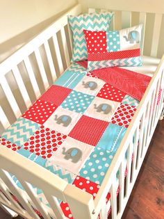 a crib bed with red, white and blue quilts on the bottom half