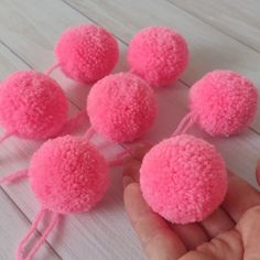 a hand is holding several pink pom - poms