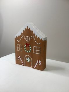 a paper bag with a gingerbread house on it and candy canes in the front