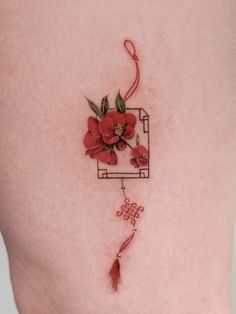 a woman's thigh with a tattoo on it that has flowers in the shape of a frame