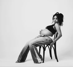 a black and white photo of a pregnant woman sitting on a chair