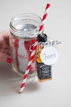 a hand holding a mason jar with a red and white striped straw next to it