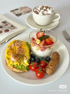 a white plate topped with food next to a bowl of fruit and a cup of coffee