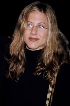 a woman with long hair wearing glasses and a black turtle neck sweater is looking at the camera