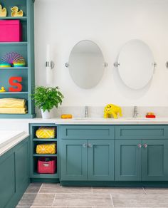 a bathroom with blue cabinets and two mirrors on the wall, along with yellow towels