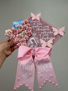 a hand holding a pink graduation cap with flowers