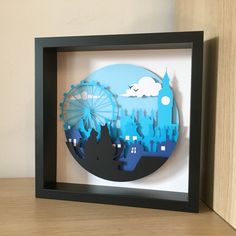 a shadow box with an image of a ferris wheel in the middle and cityscape behind it