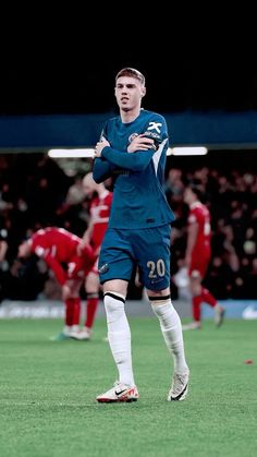 a man standing on top of a soccer field wearing a blue uniform and white socks