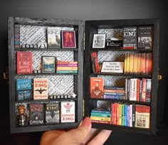 a hand holding an open book case filled with books