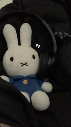 a stuffed rabbit with headphones sitting in a backpack