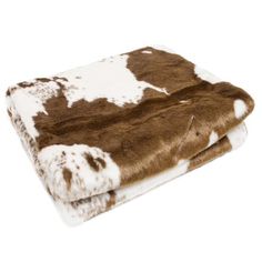 two brown and white cow hide blankets on top of each other