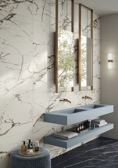 a bathroom with marble walls and flooring, two sinks under a mirror on the wall