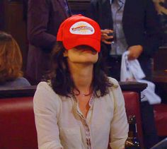 a woman wearing a red hat sitting at a table in front of a beer bottle