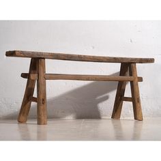 a wooden bench sitting in front of a white wall