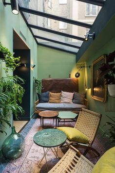 an indoor living area with green walls and plants on the floor, couches and tables