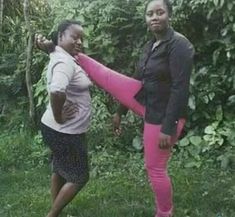 two women are standing in the grass and one is stretching her leg