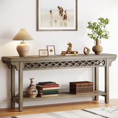 a console table with books, vases and pictures on the wall behind it in a living room