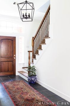 a foyer with a rug, chandelier and wooden door