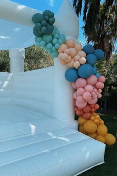 an inflatable bed with balloons attached to the top and bottom, sitting on grass