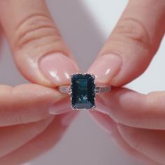 a woman's hands holding an emerald ring