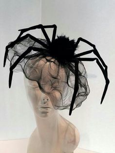 a white mannequin head wearing a black spider net hat with hair on top