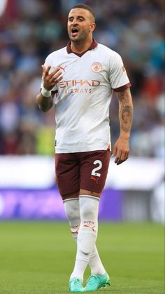 a soccer player is standing on the field with his hands out and mouth wide open