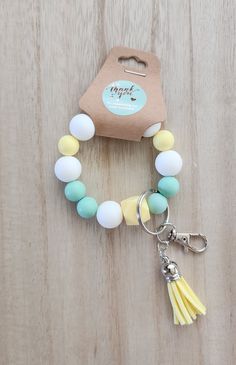 a yellow and white beaded bracelet with tassels sits on a wooden surface