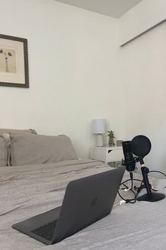 an open laptop computer sitting on top of a bed next to a camera and tripod