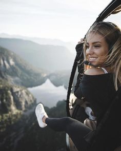 a woman is sitting in the back of a helicopter looking out at mountains and valleys