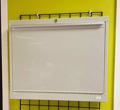 a white board mounted to the side of a yellow wall