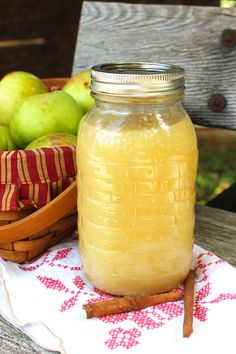 a glass jar filled with liquid sitting on top of a wooden table next to fruit