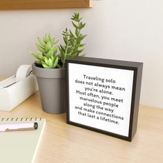 a wooden box with a quote on it sitting next to a potted succulent