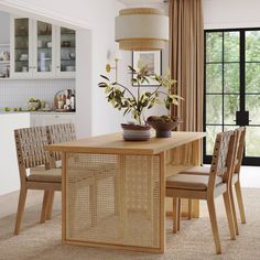 a dining room table with chairs and a vase on it in front of a window