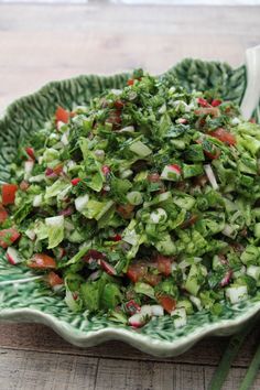 a green bowl filled with salad on top of a wooden table