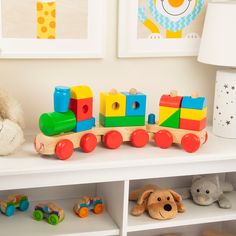 a wooden toy train sitting on top of a white shelf next to a stuffed animal