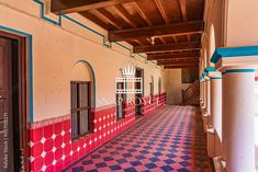 an empty hallway with red and blue tiles on the walls, and white columns in the middle