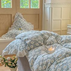 a bed with blue and white bedspread next to a vase filled with flowers