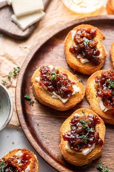 small appetizers on a wooden platter with cheese and sauce in the middle