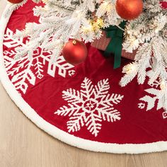 a christmas tree skirt with snowflakes and baubles on the floor next to it